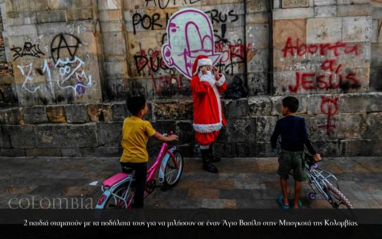 <p>2 παιδιά σταματούν με τα ποδήλατα τους για να μιλήσουν σε έναν Άγιο Βασίλη στην Μπογκοτά της Κολομβίας.</p>
